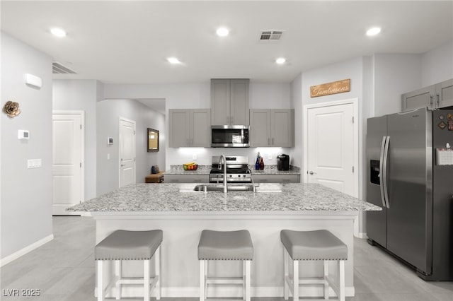 10951 Stone Crossing Ave, Las Vegas, NV 89166 - kitchen with stainless steel appliances, gray cabinets, a kitchen bar, an island with sink, and recessed lighting