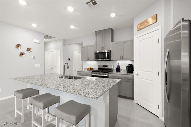 10951 Stone Crossing Ave, Las Vegas, NV 89166 - kitchen with stainless steel appliances, a sink, gray cabinets, a kitchen breakfast bar, and recessed lighting