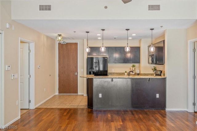 8255 Las Vegas Blvd Unit 117, Las Vegas, NV 89123 - kitchen with black fridge, a peninsula, dark wood-style flooring, light stone counters, and pendant lighting