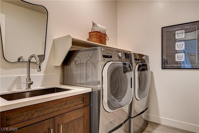 10228 Shell Star Ave, Las Vegas, NV 89135 - laundry room with washing machine and clothes dryer, baseboards, light wood-type flooring, and cabinet space