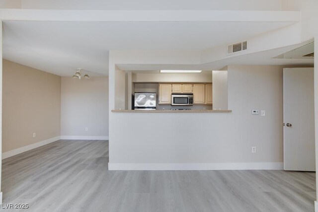 555 E Silverado Ranch Blvd Unit 2164, Las Vegas, NV 89183 - kitchen featuring stainless steel microwave, light wood-style flooring, light brown cabinetry, baseboards, and fridge