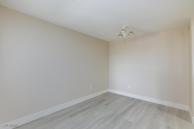 555 E Silverado Ranch Blvd Unit 2164, Las Vegas, NV 89183 - empty room featuring light wood-style floors, baseboards, and a chandelier