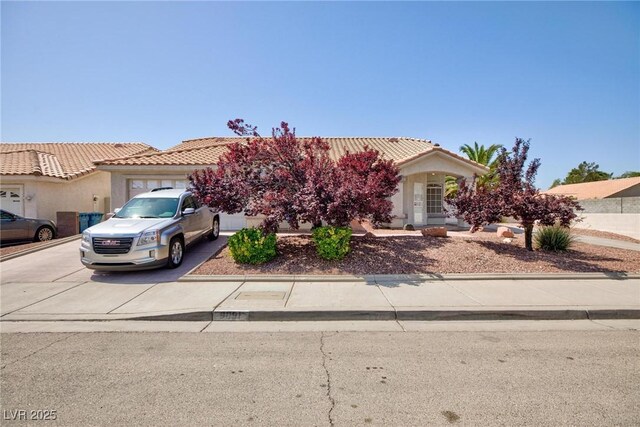 9091 W Viking Rd, Las Vegas, NV 89147 - obstructed view of property featuring driveway, a garage, a tile roof, and stucco siding