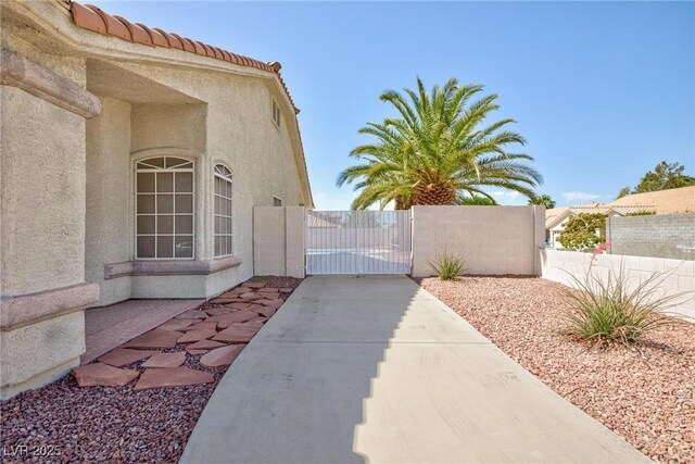 9091 W Viking Rd, Las Vegas, NV 89147 - view of side of home featuring a gate, stucco siding, and a tile roof