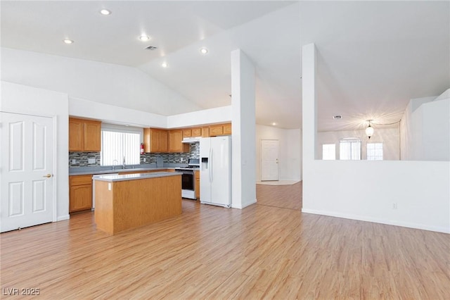 9091 W Viking Rd, Las Vegas, NV 89147 - kitchen with white appliances, open floor plan, decorative backsplash, a center island, and light wood-style flooring