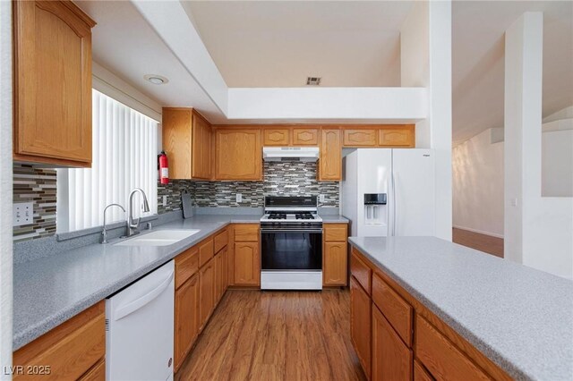 9091 W Viking Rd, Las Vegas, NV 89147 - kitchen with white appliances, under cabinet range hood, a sink, decorative backsplash, and light wood-style floors
