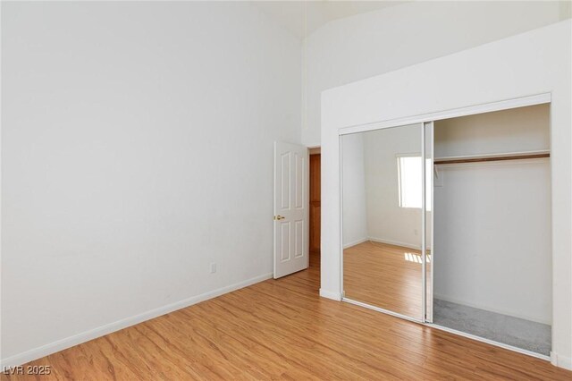 9091 W Viking Rd, Las Vegas, NV 89147 - unfurnished bedroom featuring wood finished floors, a closet, baseboards, and high vaulted ceiling