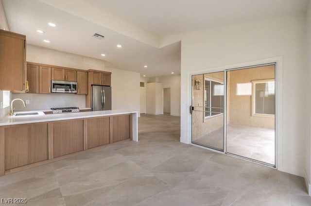 10421 Linfield Pl, Las Vegas, NV 89134 - kitchen with appliances with stainless steel finishes, a sink, a peninsula, brown cabinetry, and recessed lighting