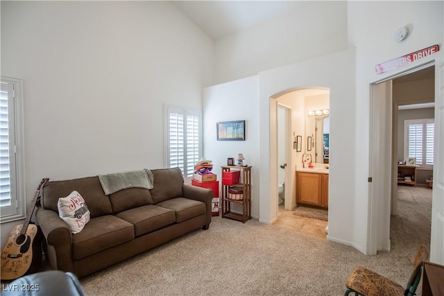 8437 Cinnamon Hill Ave, Las Vegas, NV 89129 - living room with arched walkways, high vaulted ceiling, light carpet, and baseboards