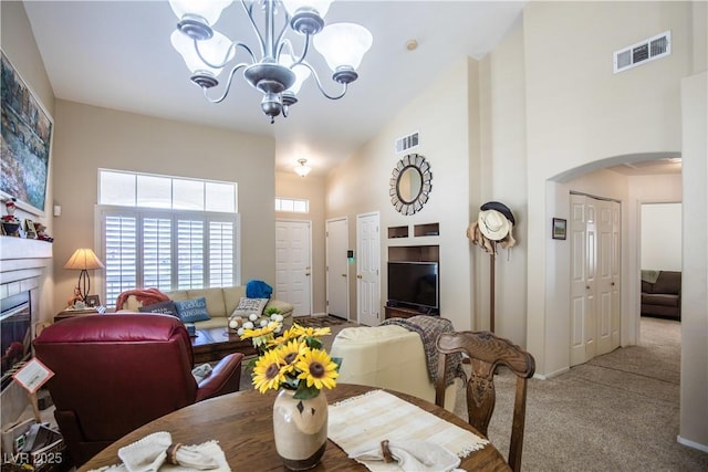 8437 Cinnamon Hill Ave, Las Vegas, NV 89129 - dining room featuring high vaulted ceiling, a chandelier, carpet flooring, arched walkways, and a glass covered fireplace