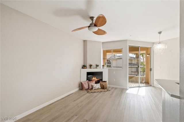 7155 S Durango Dr Unit 309, Las Vegas, NV 89113 - unfurnished living room featuring wood finished floors, a glass covered fireplace, a ceiling fan, and baseboards