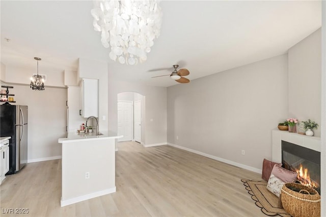 7155 S Durango Dr Unit 309, Las Vegas, NV 89113 - kitchen featuring freestanding refrigerator, arched walkways, a ceiling fan, white cabinetry, and light wood-style flooring