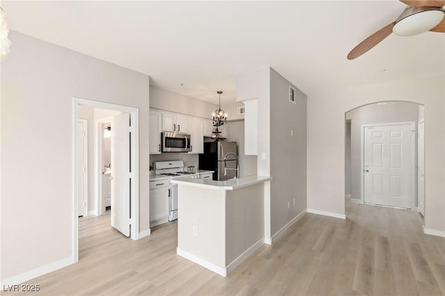7155 S Durango Dr Unit 309, Las Vegas, NV 89113 - kitchen featuring stainless steel appliances, arched walkways, light wood finished floors, white cabinets, and a ceiling fan