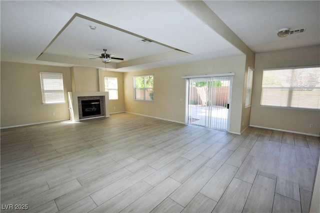 5808 Amber Station Ave, Las Vegas, NV 89131 - unfurnished living room with a tray ceiling, a ceiling fan, baseboards, and light wood-style flooring