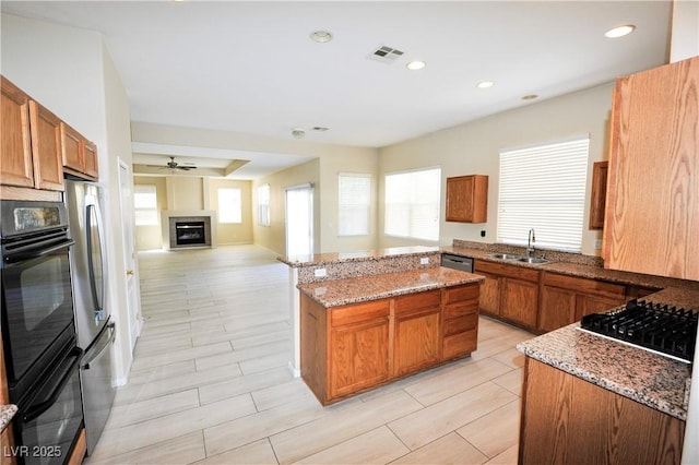 5808 Amber Station Ave, Las Vegas, NV 89131 - kitchen with stainless steel appliances, a sink, brown cabinets, light stone counters, and recessed lighting