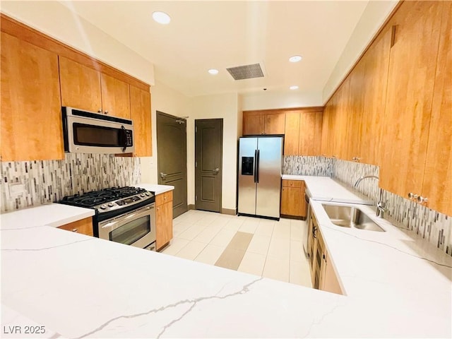 62 E Serene Ave Unit 115, Las Vegas, NV 89123 - kitchen with appliances with stainless steel finishes, a sink, tasteful backsplash, brown cabinets, and recessed lighting
