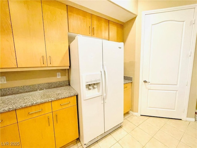 62 E Serene Ave Unit 115, Las Vegas, NV 89123 - kitchen featuring white refrigerator with ice dispenser, light tile patterned floors, baseboards, and light stone countertops