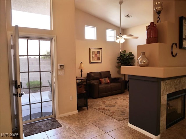 9705 Templemore Ave Unit 102, Las Vegas, NV 89129 - living room with a ceiling fan, a fireplace, baseboards, light tile patterned flooring, and high vaulted ceiling