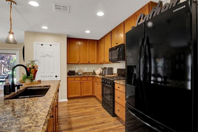 759 Star Apple Ln, Las Vegas, NV 89178 - kitchen with black appliances, a sink, light wood-style floors, light stone countertops, and decorative light fixtures