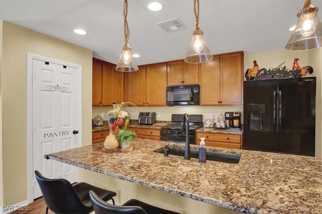 759 Star Apple Ln, Las Vegas, NV 89178 - kitchen with black appliances, a sink, light stone counters, pendant lighting, and a breakfast bar