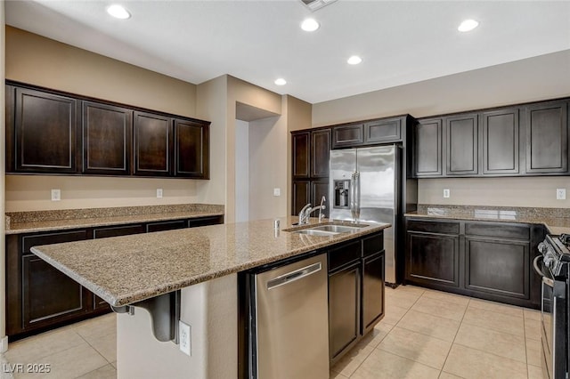 7963 Cape Brett St, Las Vegas, NV 89131 - kitchen featuring stainless steel appliances, a sink, light tile patterned floors, light stone countertops, and a kitchen island with sink