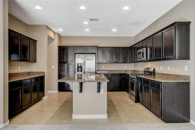 7963 Cape Brett St, Las Vegas, NV 89131 - kitchen with appliances with stainless steel finishes, light stone countertops, light tile patterned floors, a kitchen breakfast bar, and a kitchen island with sink