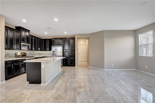 4 Lomita Heights Dr, Las Vegas, NV 89138 - kitchen featuring stainless steel appliances, tasteful backsplash, a center island with sink, baseboards, and light stone counters