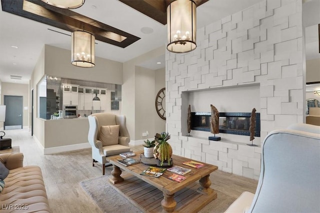 676 Otter Brook St, Henderson, NV 89011 - living room with a chandelier, light wood finished floors, baseboards, and a glass covered fireplace