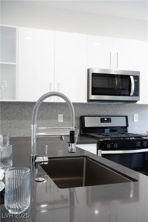10532 Redwood Ash Ave, Las Vegas, NV 89144 - kitchen with stainless steel appliances, white cabinetry, and decorative backsplash