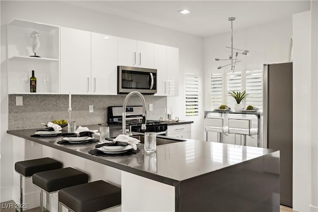 10532 Redwood Ash Ave, Las Vegas, NV 89144 - kitchen with appliances with stainless steel finishes, open shelves, a peninsula, and dark countertops