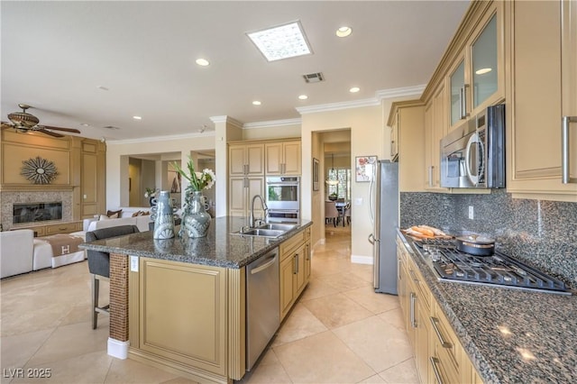 5162 Estasi St, Las Vegas, NV 89135 - kitchen featuring appliances with stainless steel finishes, a sink, crown molding, cream cabinetry, and a kitchen island with sink