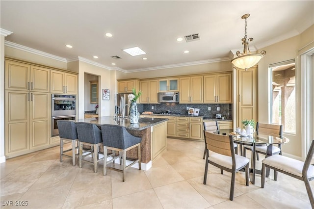 5162 Estasi St, Las Vegas, NV 89135 - kitchen featuring appliances with stainless steel finishes, ornamental molding, a breakfast bar area, decorative backsplash, and an island with sink