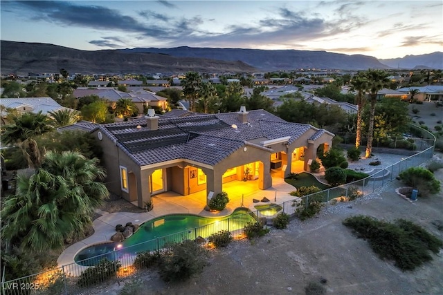 5162 Estasi St, Las Vegas, NV 89135 - back of property at dusk with a tiled roof, a mountain view, stucco siding, a fenced backyard, and a chimney
