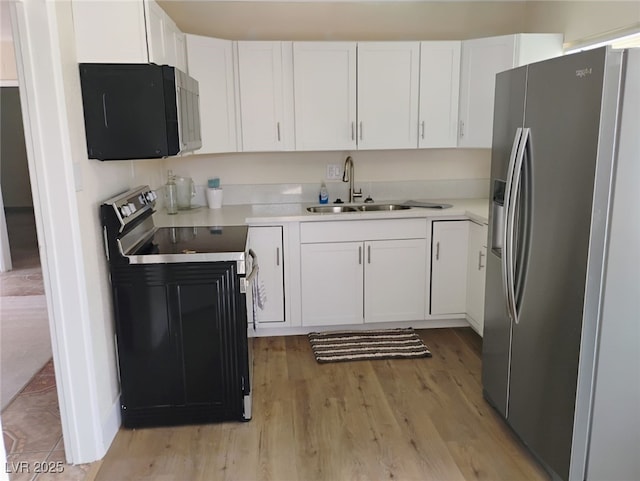 4525 Fulton Pl, Las Vegas, NV 89107 - kitchen featuring black appliances, a sink, light wood-style floors, white cabinets, and light countertops