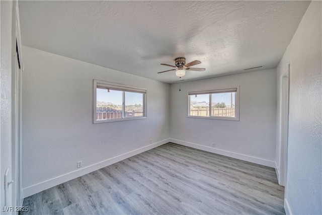 1190 W Sierra Vista Cir, Pahrump, NV 89060 - empty room with plenty of natural light, baseboards, ceiling fan, wood finished floors, and a textured ceiling