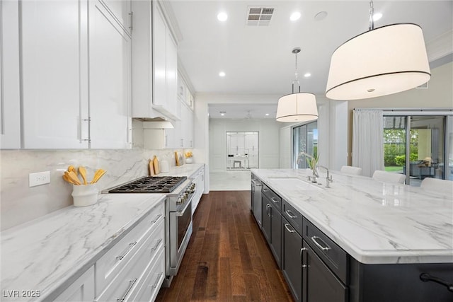 6700 Regency Stone Way, Las Vegas, NV 89148 - kitchen with high end stove, a sink, white cabinets, dark wood-style floors, and a spacious island