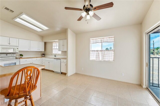 480 China St, Pahrump, NV 89048 - kitchen featuring white appliances, vaulted ceiling, light countertops, a sink, and plenty of natural light