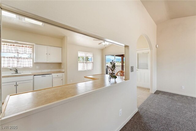 480 China St, Pahrump, NV 89048 - kitchen featuring white dishwasher, a sink, white cabinets, lofted ceiling, and light carpet
