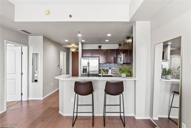 8255 Las Vegas Blvd Unit 1219, Las Vegas, NV 89123 - kitchen featuring appliances with stainless steel finishes, a peninsula, dark brown cabinetry, tasteful backsplash, and light countertops