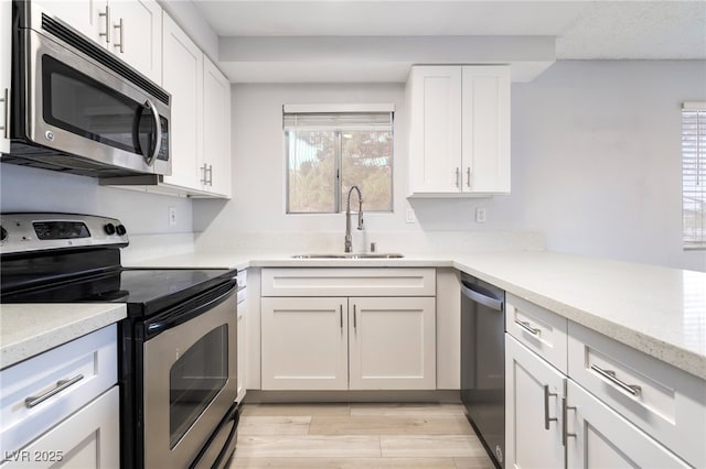 6871 Tamarus St Unit 204, Las Vegas, NV 89119 - kitchen with stainless steel appliances, a sink, white cabinetry, light wood finished floors, and light stone countertops