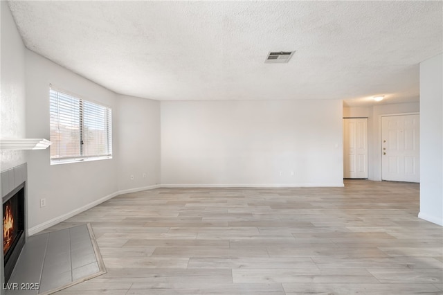 6871 Tamarus St Unit 204, Las Vegas, NV 89119 - unfurnished living room with a fireplace, a textured ceiling, light wood-style flooring, and baseboards