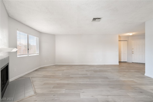 6871 Tamarus St Unit 204, Las Vegas, NV 89119 - unfurnished living room with a textured ceiling, a fireplace, light wood-style flooring, and baseboards