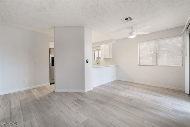 6871 Tamarus St Unit 204, Las Vegas, NV 89119 - unfurnished living room featuring a ceiling fan, light wood-style floors, a textured ceiling, and baseboards