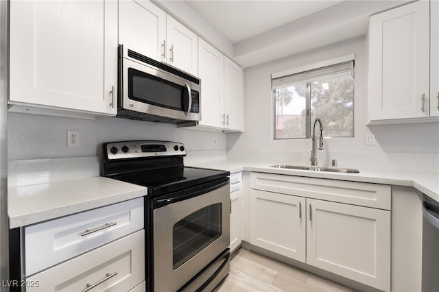 6871 Tamarus St Unit 204, Las Vegas, NV 89119 - kitchen featuring stainless steel appliances, a sink, white cabinetry, light wood finished floors, and light stone countertops