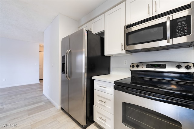 6871 Tamarus St Unit 204, Las Vegas, NV 89119 - kitchen featuring appliances with stainless steel finishes, white cabinetry, light countertops, light wood-style floors, and baseboards