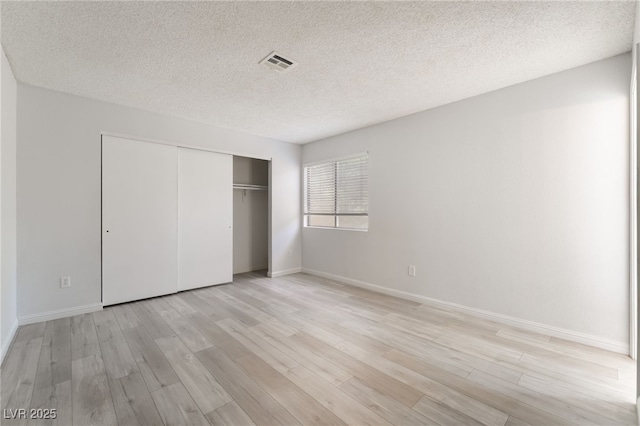 6871 Tamarus St Unit 204, Las Vegas, NV 89119 - unfurnished bedroom featuring light wood-style flooring, a textured ceiling, baseboards, and a closet