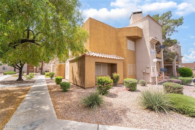 6871 Tamarus St Unit 204, Las Vegas, NV 89119 - view of front facade featuring a chimney, stucco siding, and a tiled roof