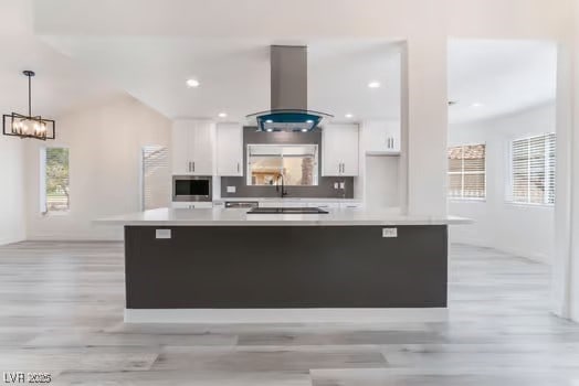 2553 Showcase Dr, Las Vegas, NV 89134 - kitchen with island range hood, white cabinetry, light wood-type flooring, plenty of natural light, and recessed lighting