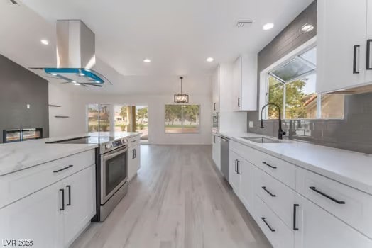 2553 Showcase Dr, Las Vegas, NV 89134 - kitchen with appliances with stainless steel finishes, a sink, island exhaust hood, light wood-style flooring, and white cabinetry