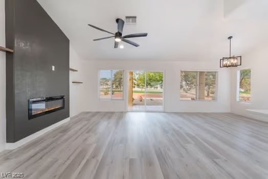 2553 Showcase Dr, Las Vegas, NV 89134 - unfurnished living room with light wood finished floors, a large fireplace, ceiling fan, a chandelier, and vaulted ceiling